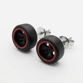 A pair of stud earrings designed to look like miniature black car wheels with a red inner rim, featuring silver-tone metal posts and backing, shown on a clean white background.