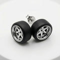 A pair of stud earrings designed to look like miniature car wheels, featuring black tires and silver multi-spoke rims, displayed on a clean white surface.
